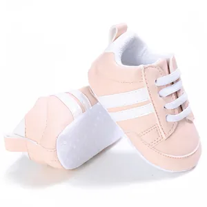 Vista detallada de zapatos rosas para caminar de bebés con dos franjas blancas