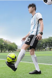 Scatto d'azione di un ragazzo che gioca a calcio con scarpe da calcio nere professionali.
