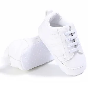Detalle de zapatos blancos para bebé con suela blanda y puntos antideslizantes.
