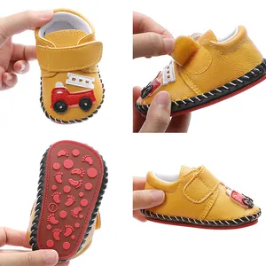 Gros plan sur des chaussures de marche jaunes pour bébé avec motif camion de pompier.