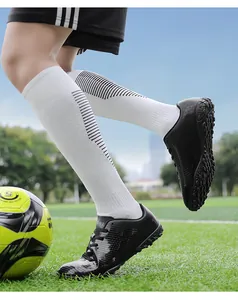 Dettaglio di scarpe da calcio professionali per bambini su un campo in erba sintetica