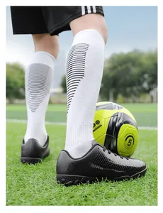 Dettaglio scarpe da calcio nere per bambini e pallone taglia 5 su campo verde