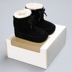 Detail view of black infant snow boots with warm white faux fur lining on a display box