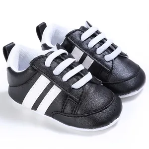 Detalle de cerca de los zapatos de bebé negros con rayas blancas y suelas muy suaves
