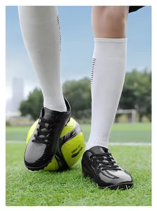 Vista dettagliata di scarpe da calcio nere per bambini su un campo di erba verde