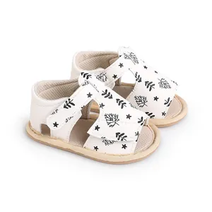 Detailed view of white baby sandals featuring black leaf and star print patterns