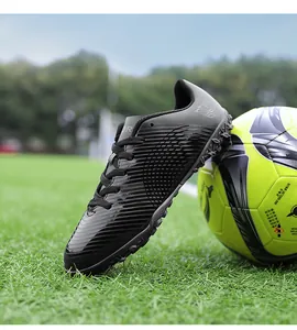 Vista dettagliata di scarpe da calcio professionali nere per bambini su un campo da calcio