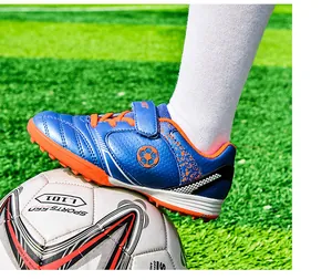 Nahaufnahme eines blau-orangen Kinder-Fußballschuhs auf einem Fußball im Detail.