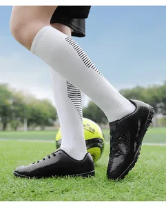 Dettaglio di scarpe da calcio per bambini nere e calzettoni sportivi su campo d'erba