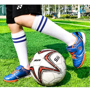 Action-Aufnahme von blauen Kinder-Fußballschuhen und gestreiften Socken auf Rasen