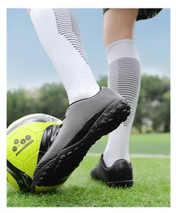 Dettaglio scarpa da calcio nera per bambini con suola strutturata su erba