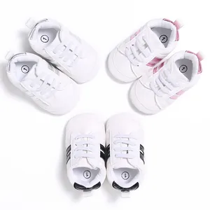 Detalle de zapatillas de bebé blancas con rayas laterales rosas, plateadas y negras