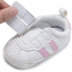 Close-up view of white baby walking shoe with adjustable hook and loop fastener detail