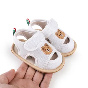 Nahaufnahme von weißen Baby-Sandalen mit Mesh-Obermaterial und Bären-Stickerei