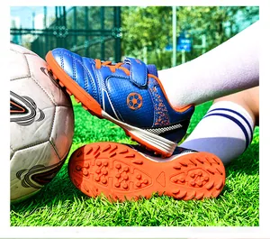 Detailaufnahme der blauen Kinder-Fußballschuhe mit kräftiger orangefarbener Noppensohle