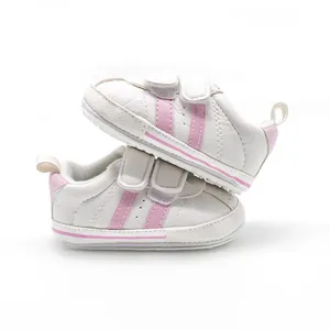 Detailed side view of white baby walking shoes featuring pink stripes and dual Velcro straps
