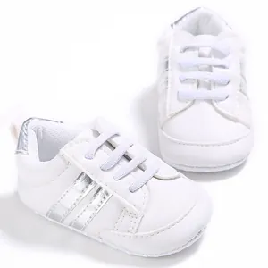 Vista detallada de zapatos blancos para bebé con rayas plateadas y suela blanda.