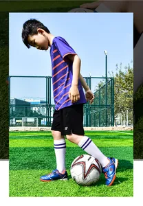 Action-Foto eines Kindes mit blauen Kinder-Fußballschuhen auf einem Profi-Sportplatz