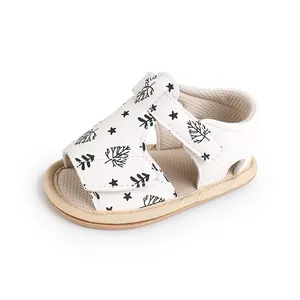 White infant walking sandals with black leaf pattern and adjustable Velcro strap closure