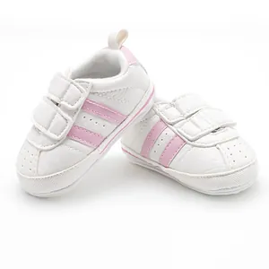 Close-up of white baby walking shoes with pink stripes and velcro straps