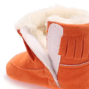 Close-up detail showing soft white fleece lining and fringe on orange baby snow boots