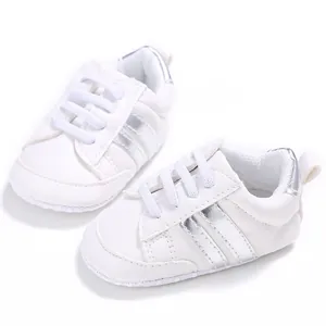Detalle de zapatos blancos para bebé con suela blanda y rayas plateadas metálicas