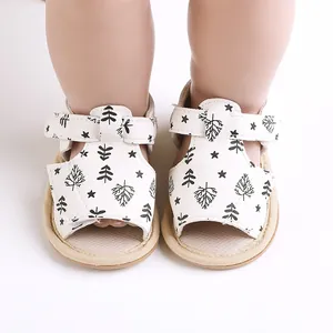 Close-up view of white infant walking shoes featuring black tree and star patterns