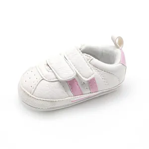 White baby walking sneakers with pink stripes and adjustable velcro straps detail