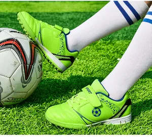 Aktionsfoto von leuchtend grünen Kinder-Fußballschuhen für Kunstrasen auf Spielfeld.