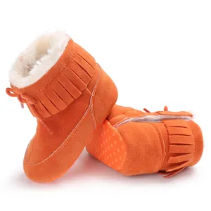 Detailed view of orange baby winter snow boots with warm faux fur lining and tassels