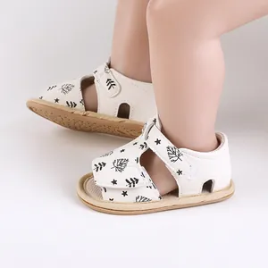 Detailed view of white baby beach sandals with leaf patterns and hook-and-loop straps.