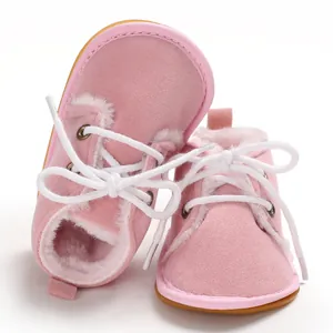 Nahaufnahme von rosa Baby-Winterstiefeln mit weichem Kunstfellfutter und weißen Schnürsenkeln.
