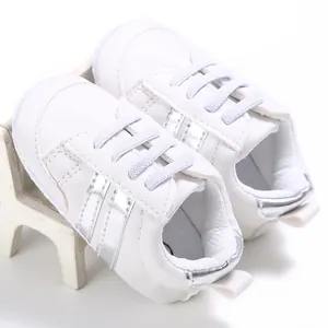 Detalle de zapatos blancos para caminar de bebé con suela blanda y rayas plateadas