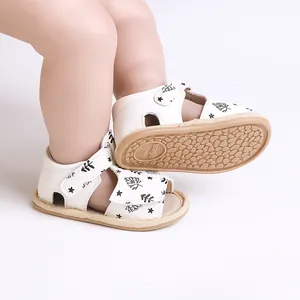 Close-up detail of white baby sandals with black leaf print and soft non-slip sole texture
