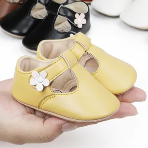 Close-up of cute yellow infant princess shoes with flower detail and rubber soles.
