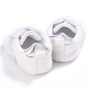Vista trasera detallada de zapatillas blancas para bebés con talón plateado metalizado.