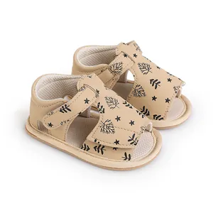 Soft-soled baby sandals with black leaf and star print in a neutral beige color.