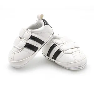 Close-up of white baby walking shoes with two black stripes and rubber soles