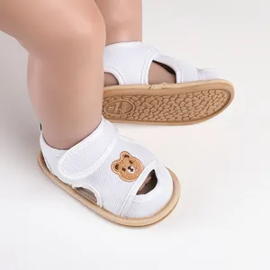 Detail von atmungsaktiven weißen Baby-Sandalen aus Mesh mit süßem Bären-Stickerei.