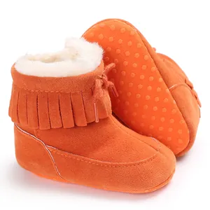 Detailed view of orange infant snow boots featuring soft fleece lining and fringe décor
