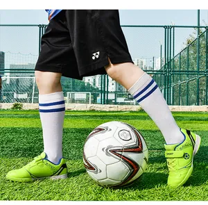 Detailansicht grüner Kinder-Fußballschuhe auf einem Kunstrasen-Spielfeld
