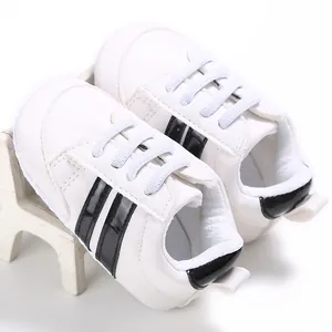 Vista detallada de zapatillas blancas para bebé con rayas negras y suelas blandas