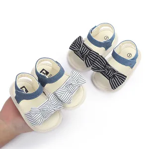 Nahaufnahme von Baby-Lauflernsandalen mit gestreifter Schleife und weicher Sohle.