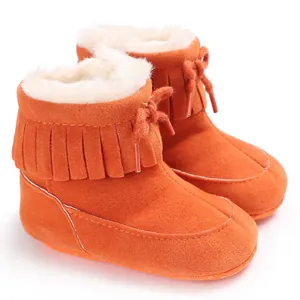 Close-up of orange baby winter snow boots with warm plush lining and fringe decor