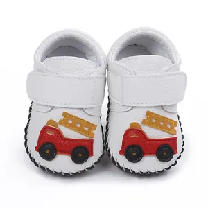 Gros plan de chaussures pour bébé blanches avec applique camion de pompier rouge