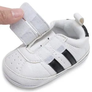 Close-up of white baby walking shoe featuring adjustable hook and loop closure detail.
