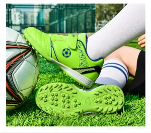 Detailansicht neongrüner Kinder-Fußballschuhe auf Gras mit Sohle und Obermaterialien.
