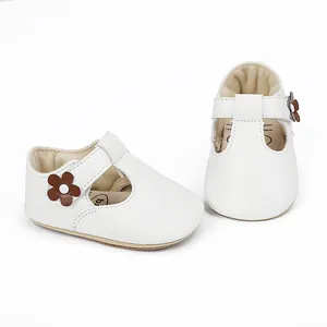Detailed view of white baby princess shoes with a small brown flower accent