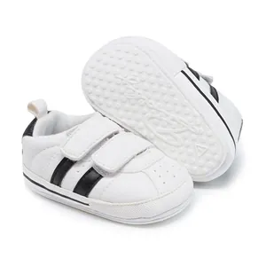Detail showing white baby walking shoes with two black stripes and non-slip rubber sole