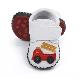 Vue détaillée des chaussures de marche pour bébé blanches avec applique camion de pompier.